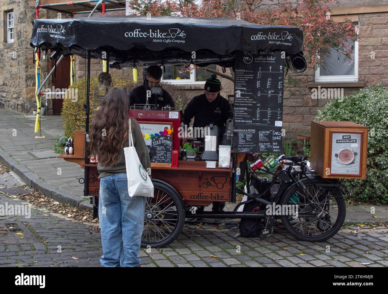 Edinburgh: a young woman awaits her order at a mobile coffee stall, the coffee-bike, at the western end of Bell's Brae bridge in Dean Village. Stock Photo