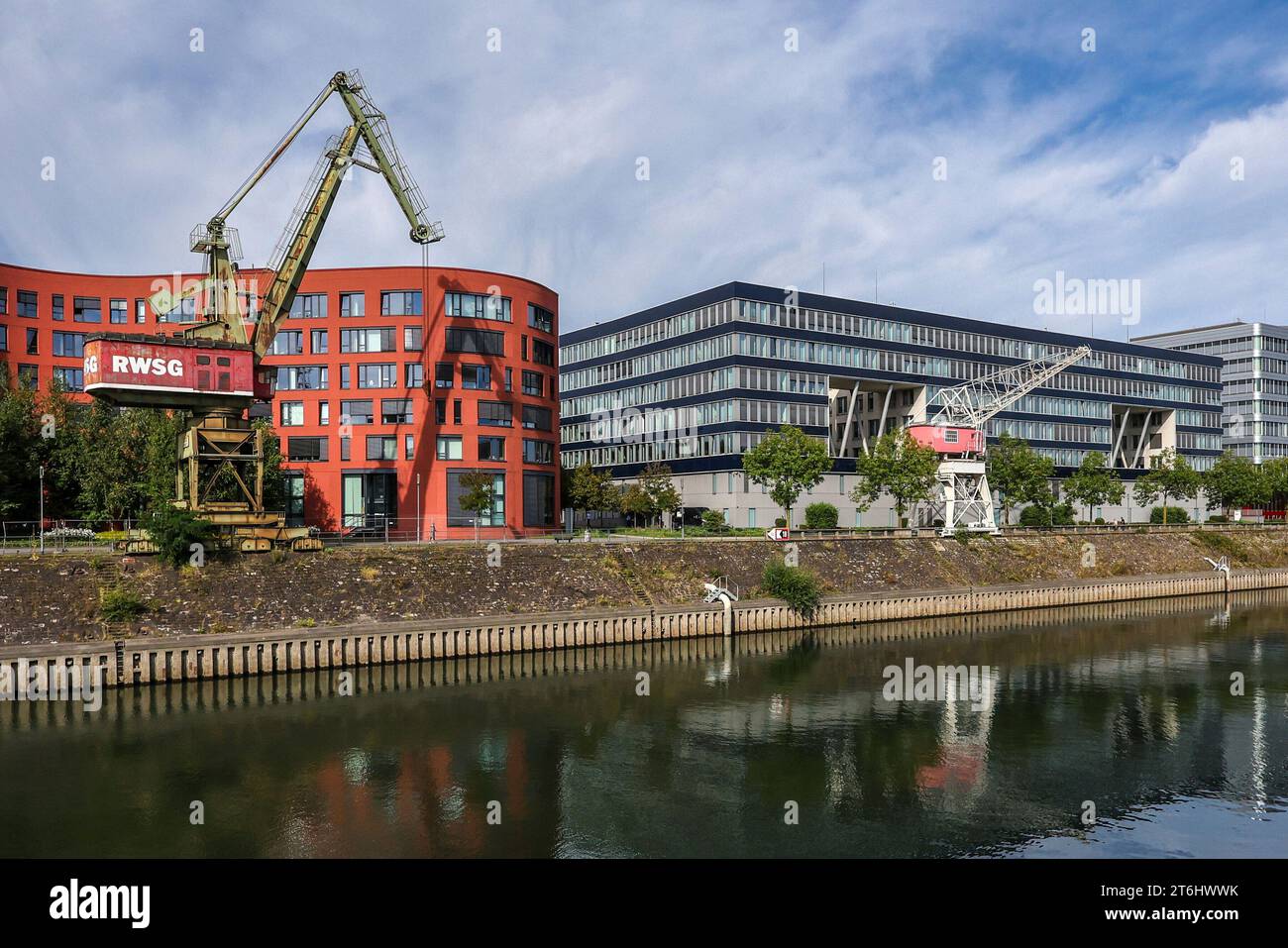 Duisburg, Ruhr area, North Rhine-Westphalia, Germany - Duisburg inner harbor with the wave-shaped building of the North Rhine-Westphalia state archive and old harbor cranes. On the right modern office buildings. Stock Photo