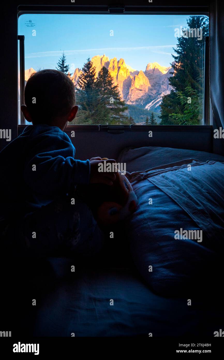 Child observe the mountains in the camper, Europe, Italy, Trentino Alto Adige, Trento province, Pozza di Fassa Stock Photo