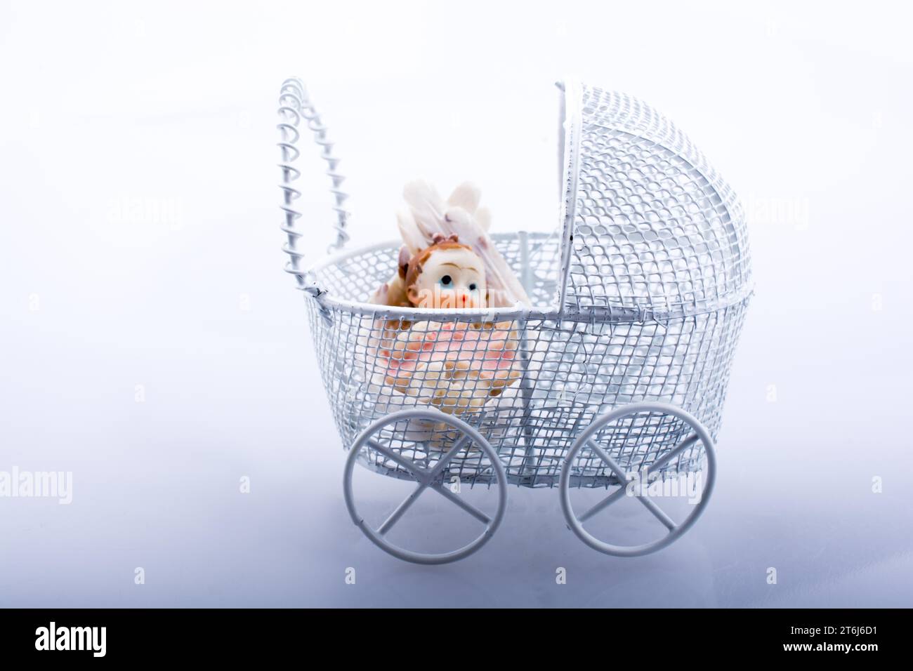 Little baby doll in baby carriage on a white background Stock Photo