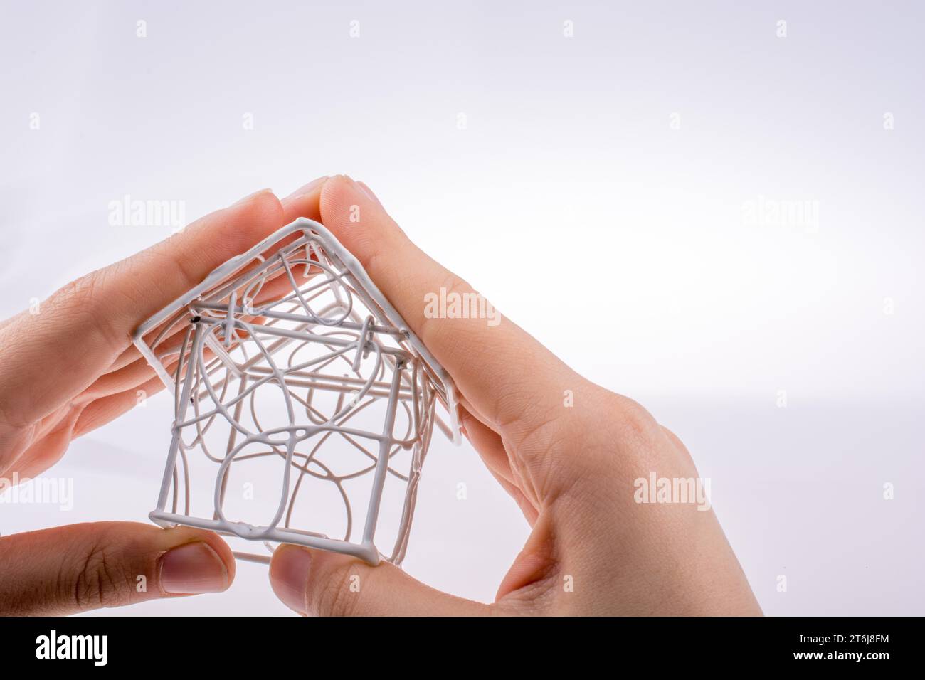 Little model house made of white metal wire in hand Stock Photo