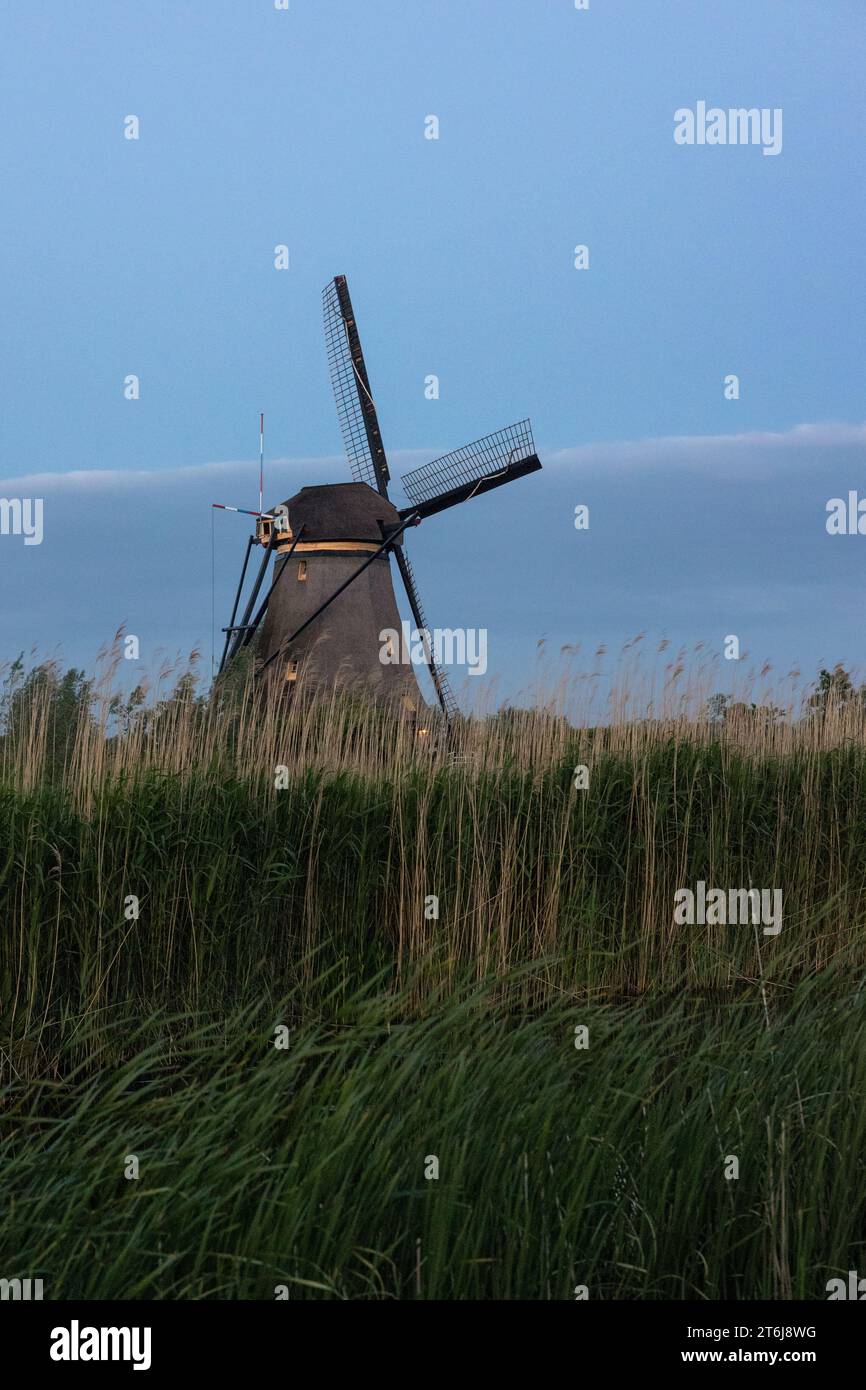 Beautiful wooden windmills at sunset in the Dutch village of Kinderdijk. Windmills run on the wind. The beautiful Dutch canals are filled with water. Stock Photo