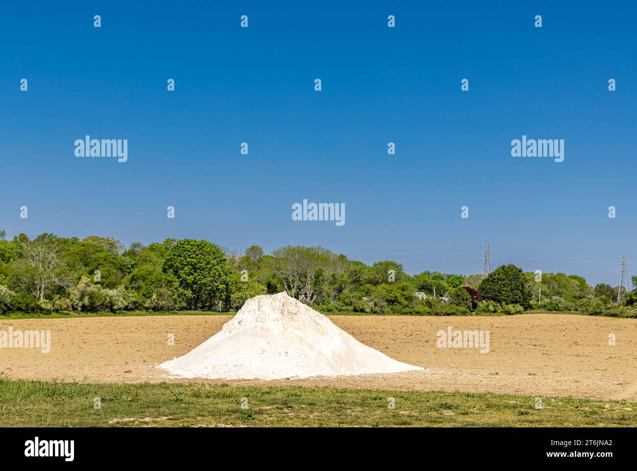 large pile of white material dumped in a newly plowed field Stock Photo