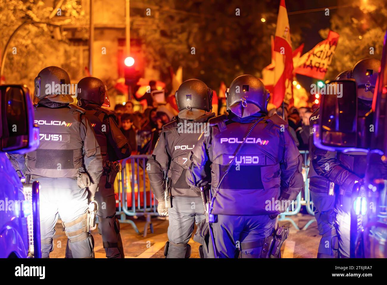 A group of national police observes the protesters standing behind the security fence during the protest against the amnesty of the Catalan independence politicians and against President Pedro Sanchez in front of the headquarters of the Spanish socialist workers' party along Ferraz Street. Stock Photo
