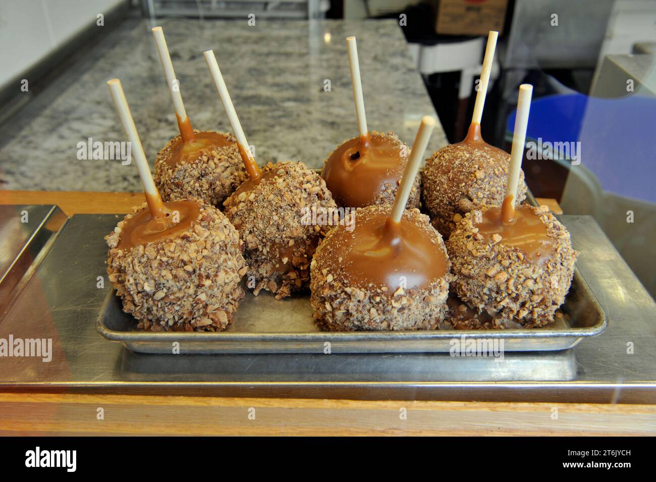 Caramel apples dipped in chopped nuts on display at candy stand in the