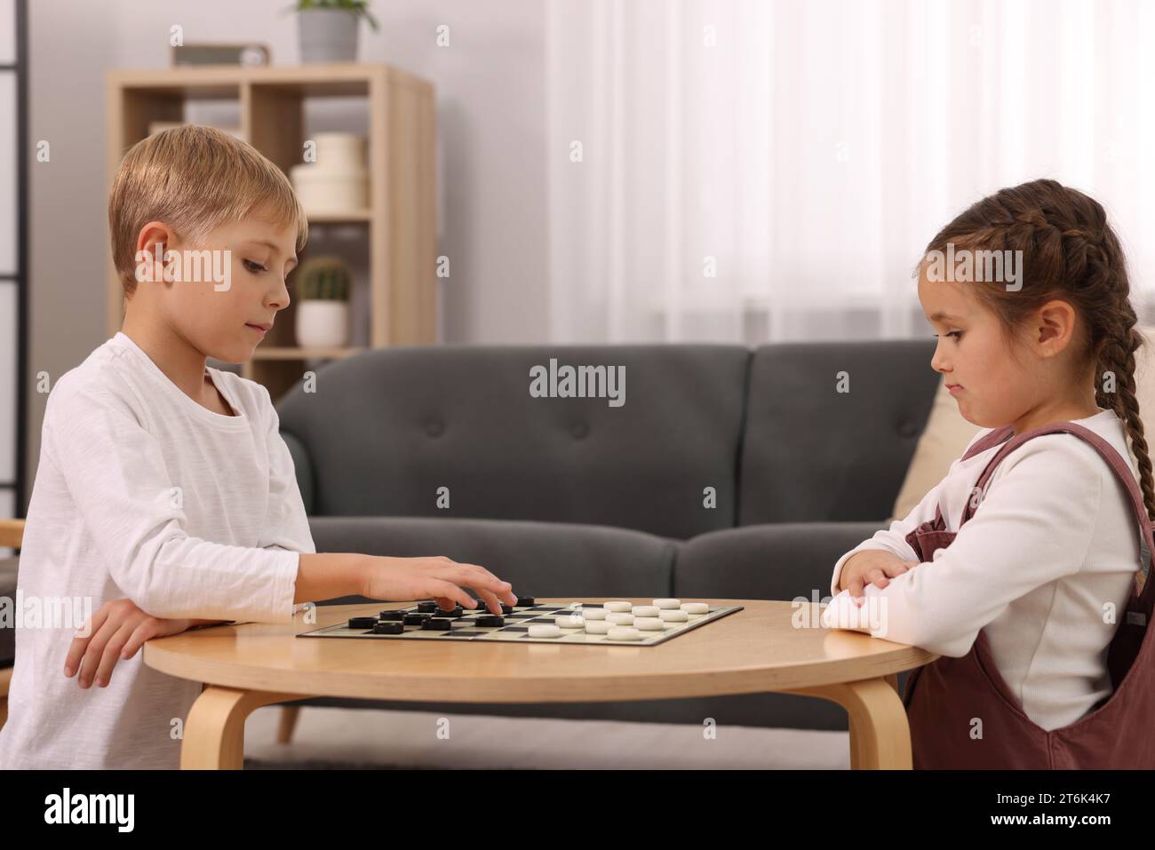Children playing checkers at coffee table in room Stock Photo - Alamy