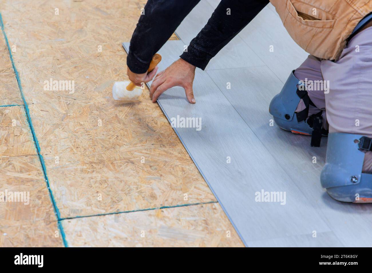 An installation worker installs vinyl laminate flooring in new home Stock Photo