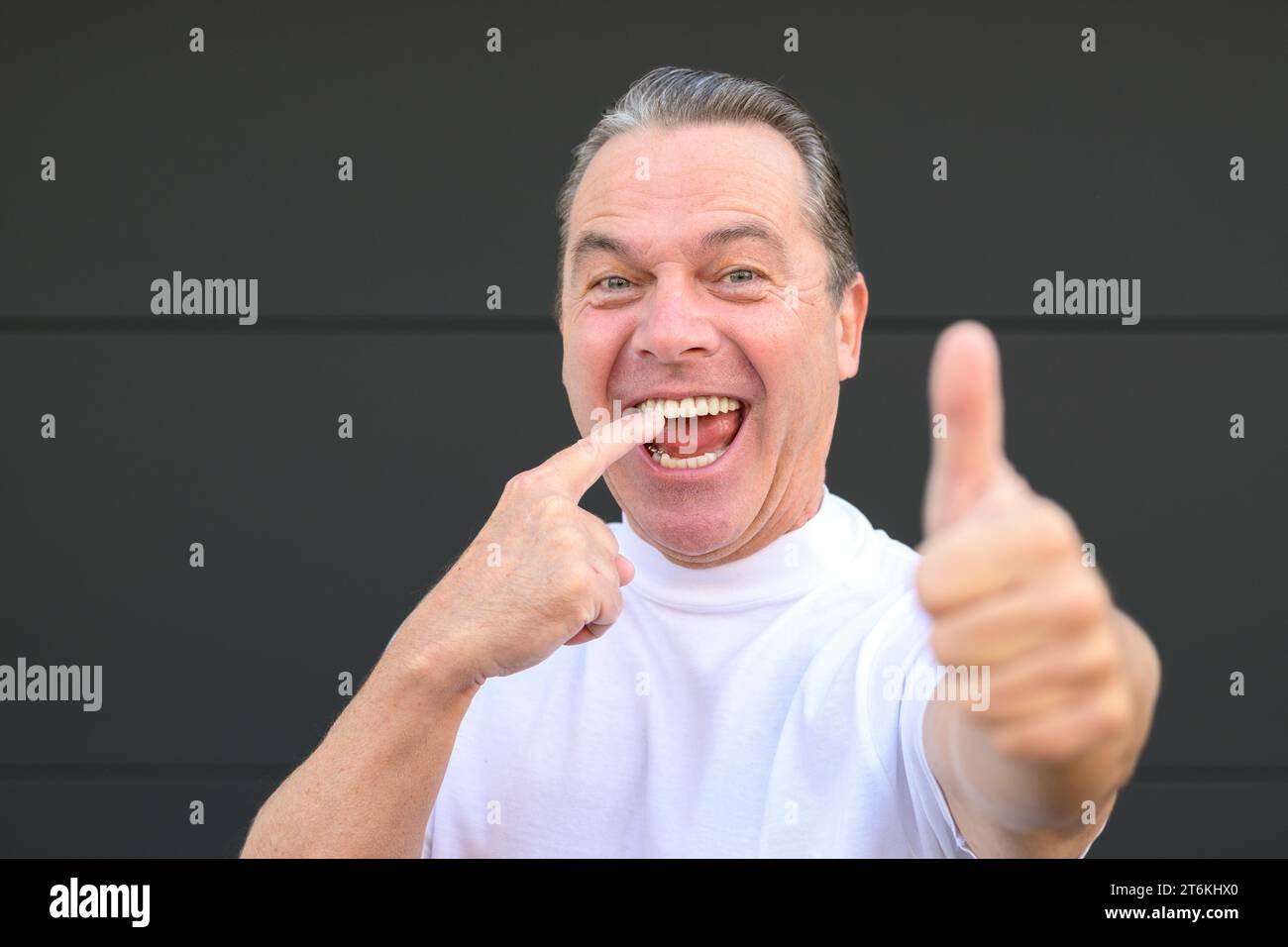 Man with a big smile is pointing on his teeth because this made the best dentist in town Stock Photo