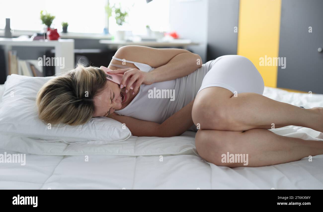 Unknown woman in white underwear experiences severe pain and abdominal  cramps at home in morning. Sick woman suffering from diarrhea, menstrual  cramps, food poisoning, gastritis or constipation. Stock Photo