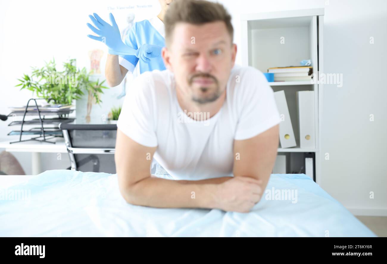 Doctor putting on protective glove for rectal examination of man Stock Photo