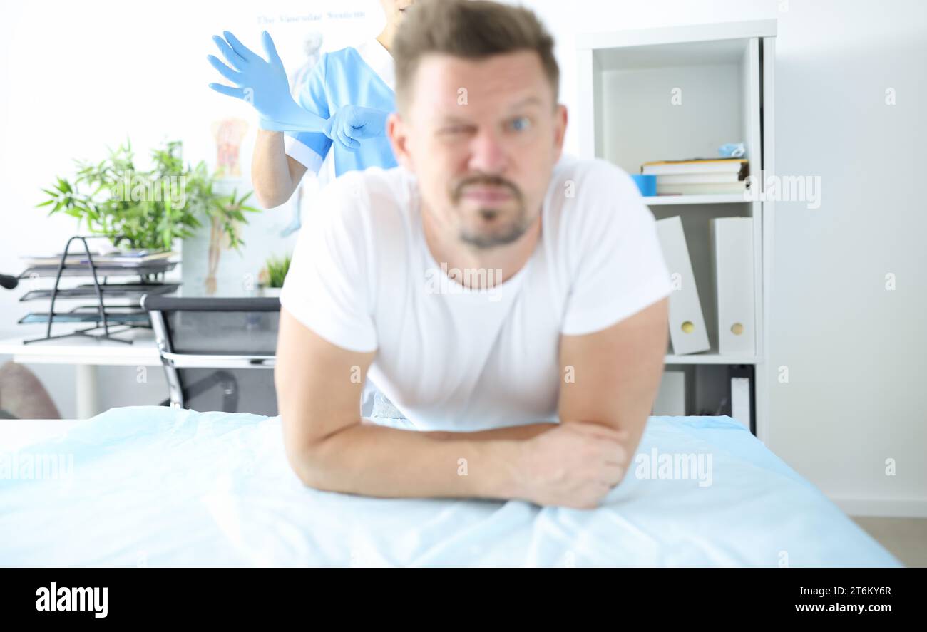 Doctor putting on protective glove for rectal examination of man