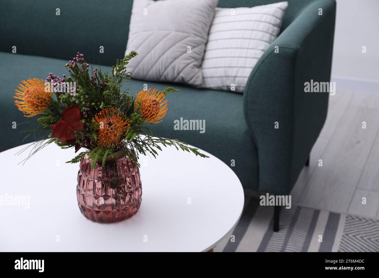 Vase with bouquet of beautiful leucospermum flowers on white coffee table in living room Stock Photo