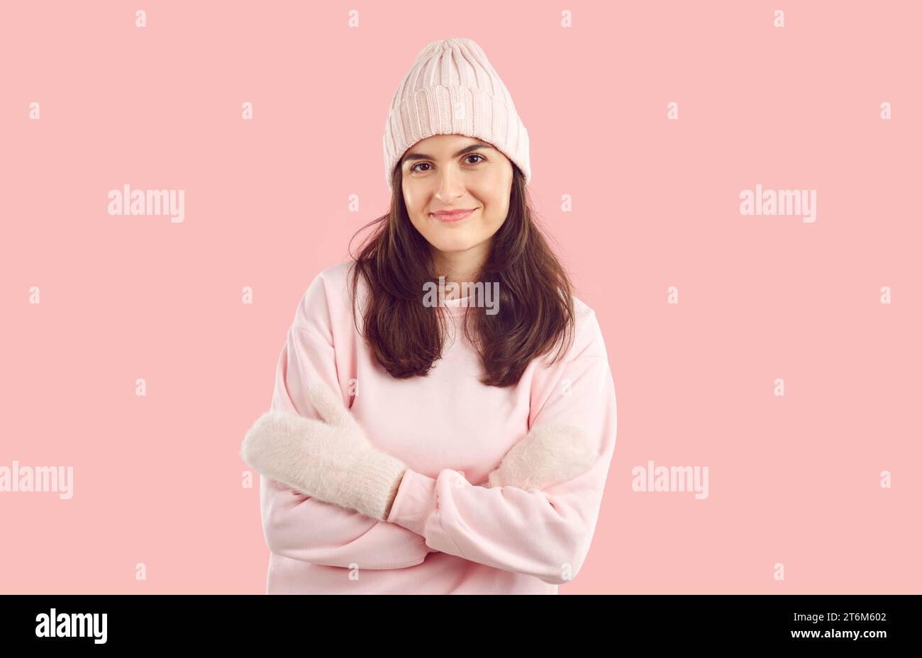 Portrait of happy beautiful young woman in warm pink winter hat, sweatshirt and mittens Stock Photo