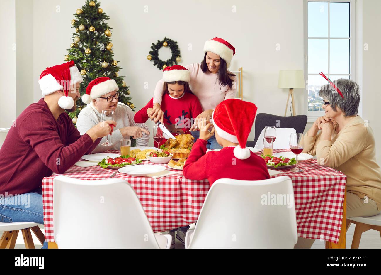 Christmas Thanksgiving dinner with turkey in big family aitting at table in Xmas interior at home. Stock Photo