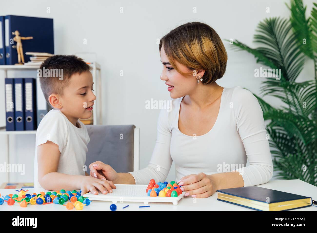 a boy with a female psychologist in the office plays educational games Stock Photo