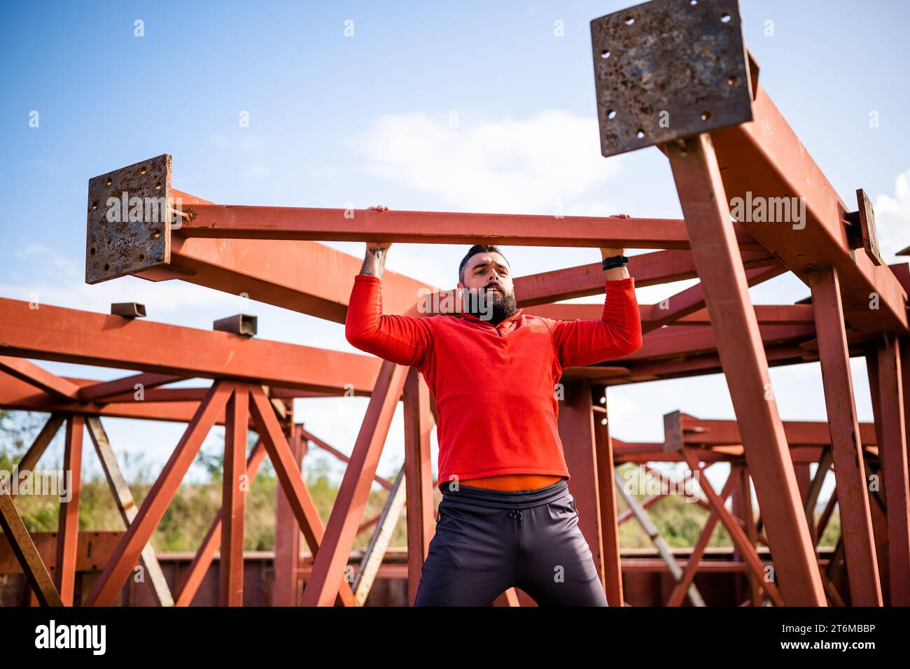 Young man is exercising outdoor. He is doing pull-ups. Stock Photo