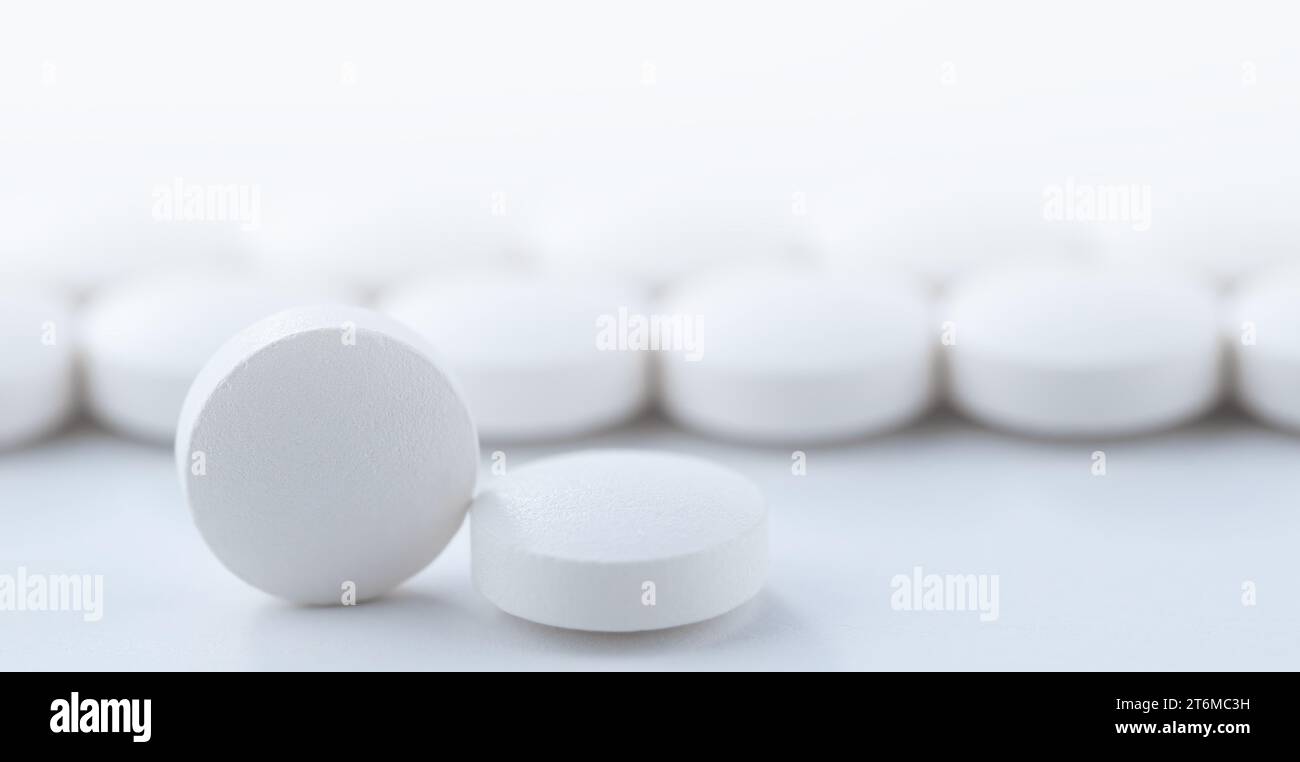 Close up white pills scattered on the table. Medicine, medical insurance or pharmacy concept Stock Photo