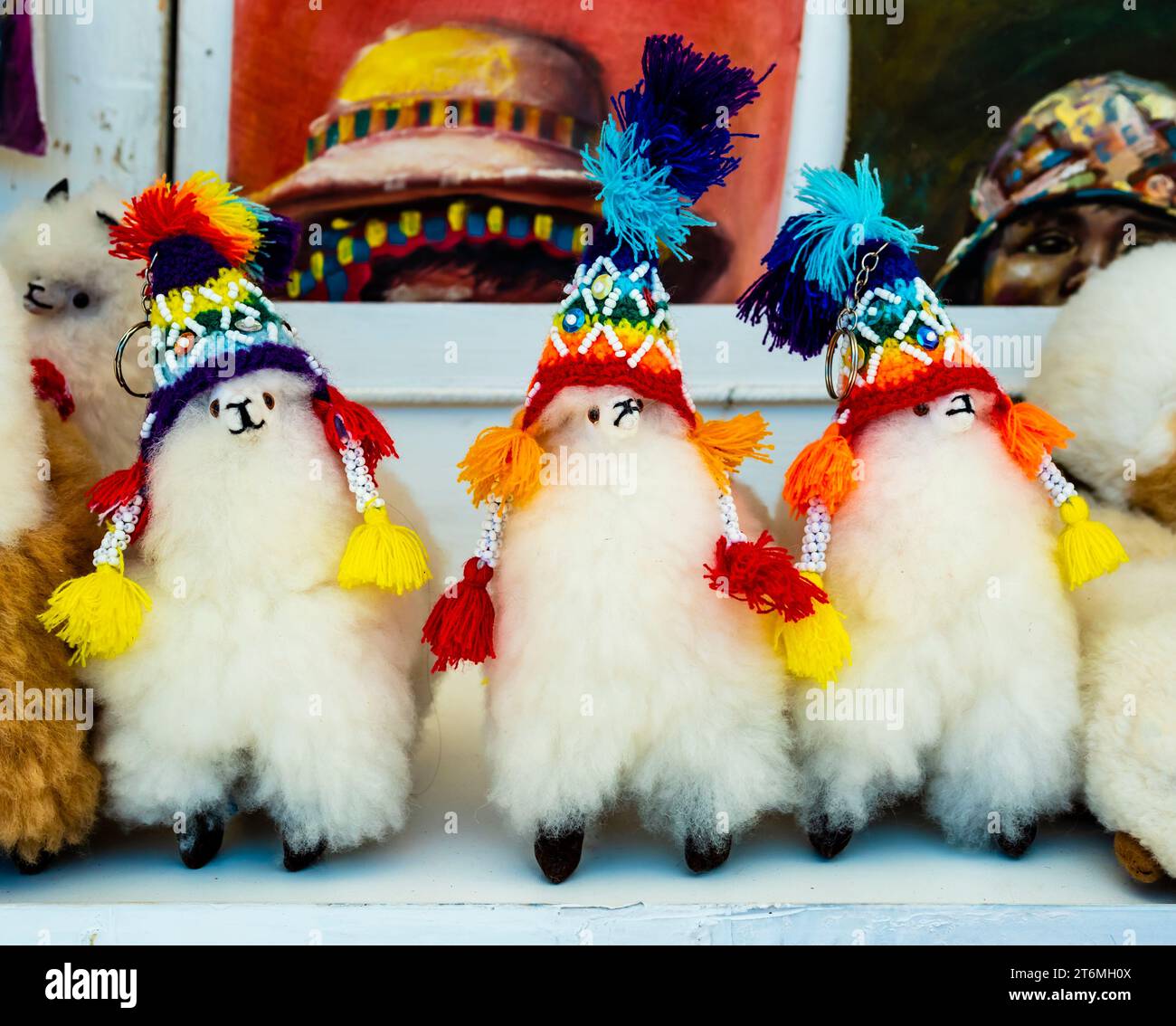 Row of alpaca plush toys with traditional rainbow-colored hats, Pisac traditional market, Peru Stock Photo