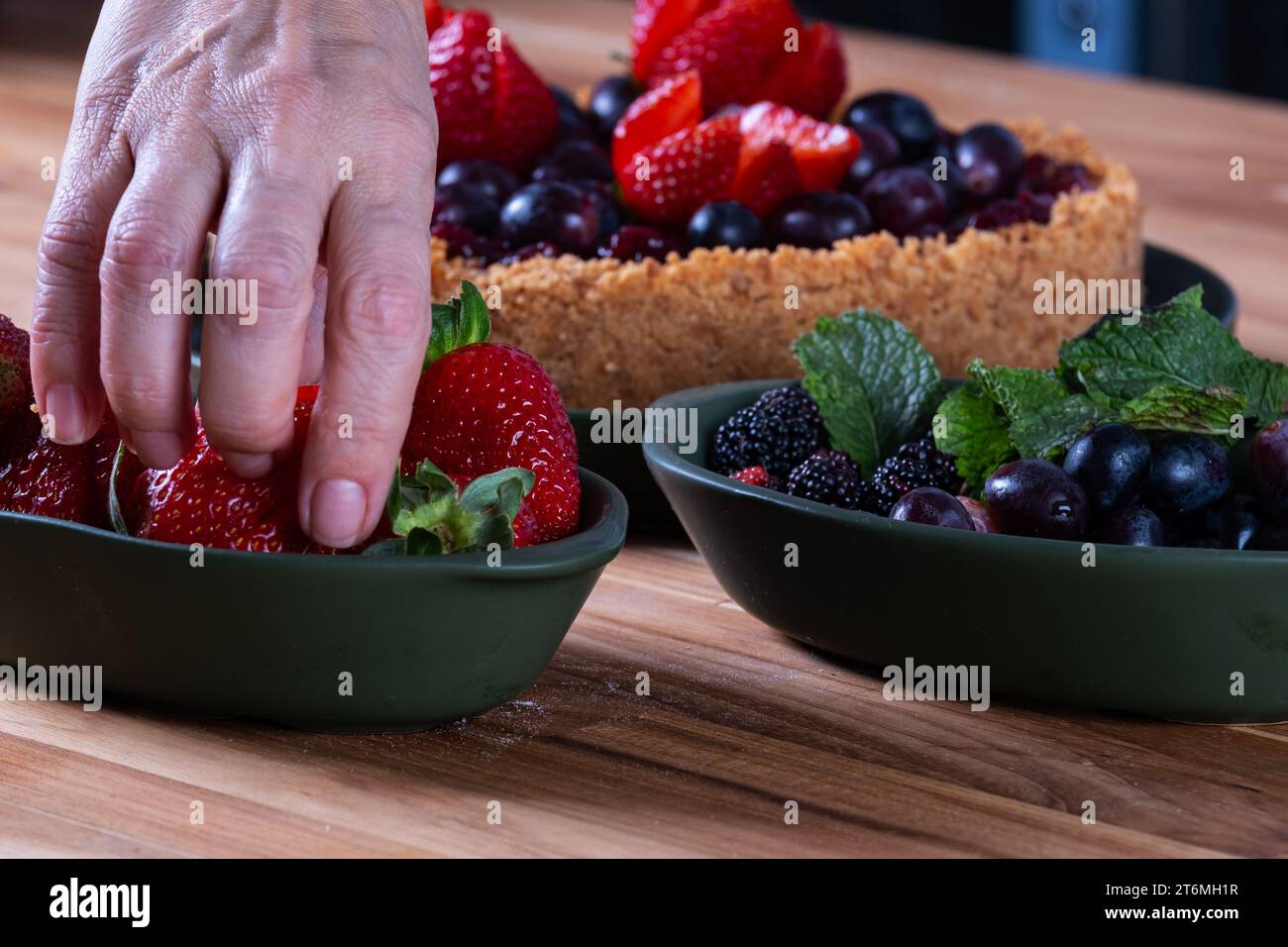 female hands decorating a berry pie with fruits. Stock Photo