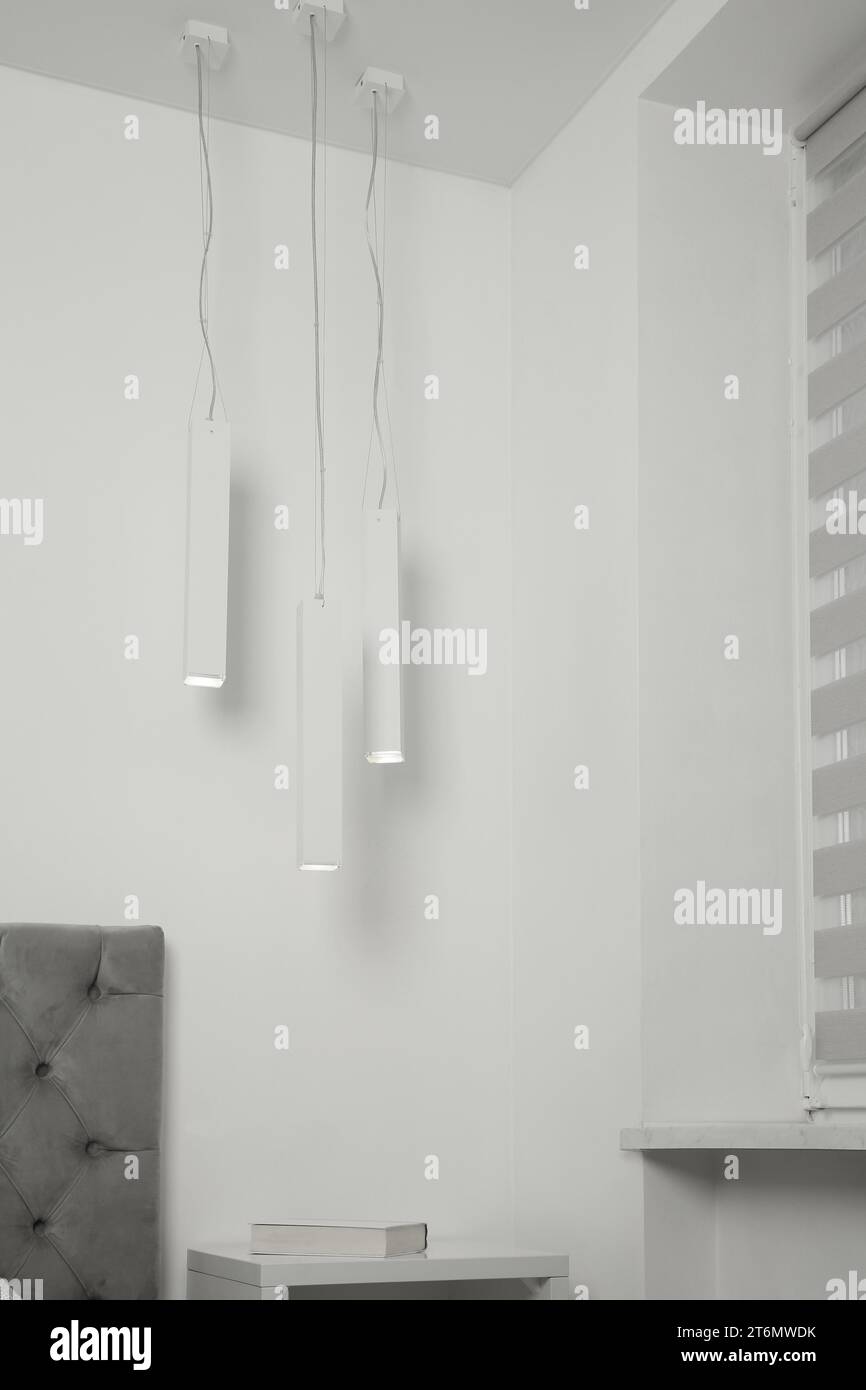 Stylish pendant lamps hanging over nightstand in light room Stock Photo Alamy