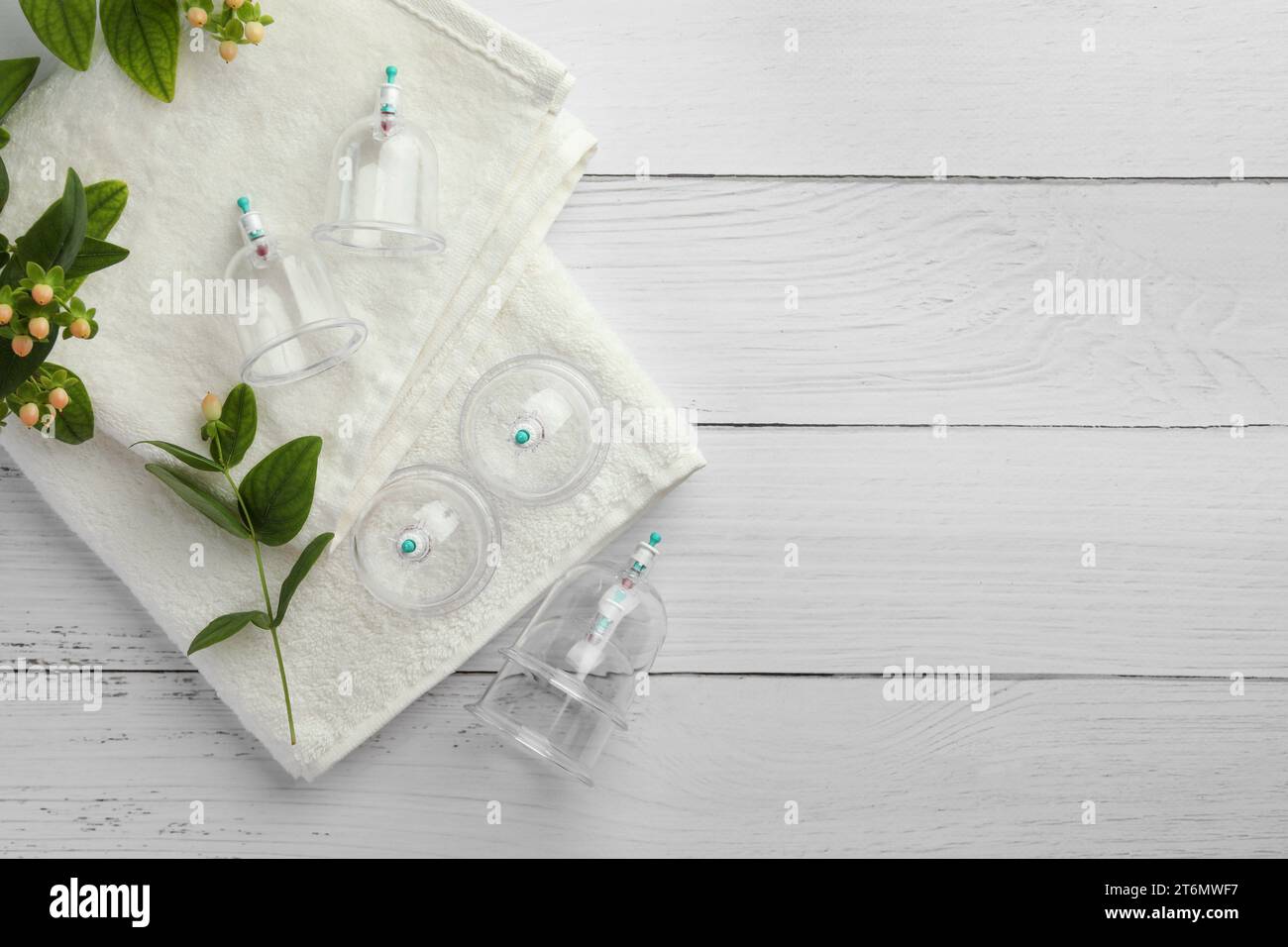 Cupping therapy. Plastic cups, towels and hypericum perforatum berries on white wooden table, flat lay. Space for text Stock Photo