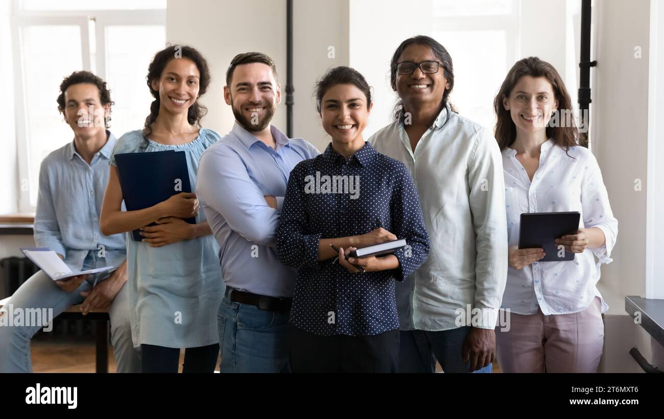 Multiethnic confident group of happy employees holding notebooks Stock Photo