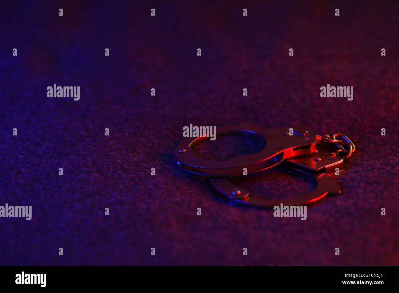 Closed handcuffs on the dark surface at night with police car lights high contrast image Stock Photo