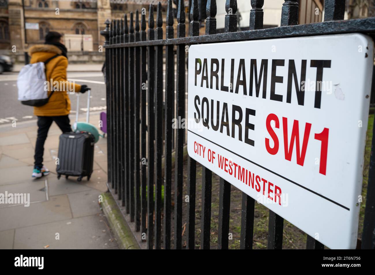 A person wheeling a suitcase passes a street sign for Parliament Square, London, UK Stock Photo
