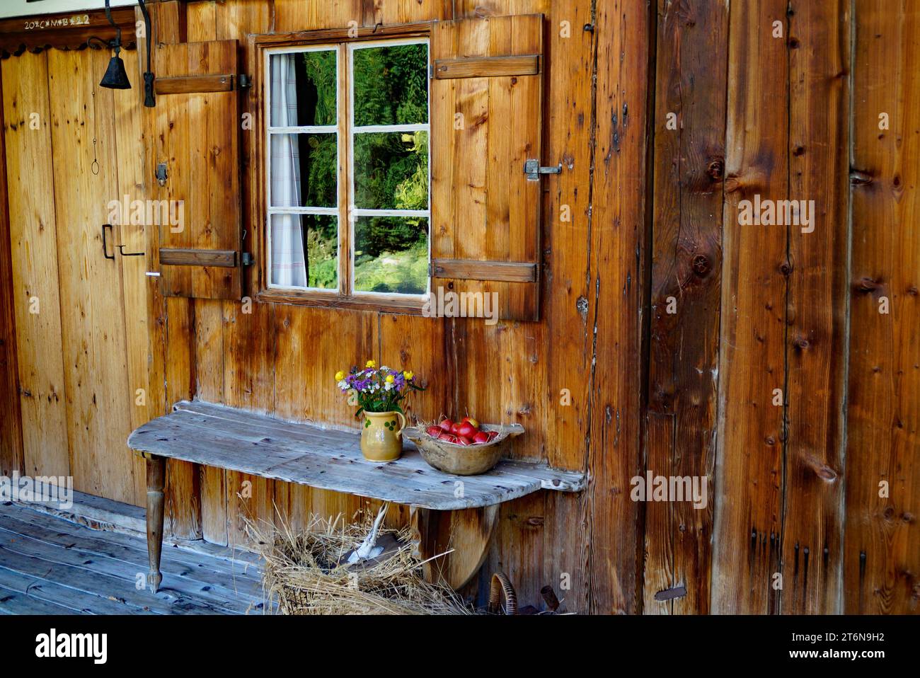 rustic countryside scenery with an old yellow vase with field flowers and red apples in the basket on the wooden bench in Bavarian village Schwangau Stock Photo