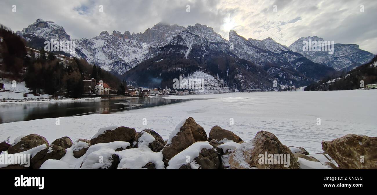 View of the frozen lake of Alleghe with the town in the background. Stock Photo