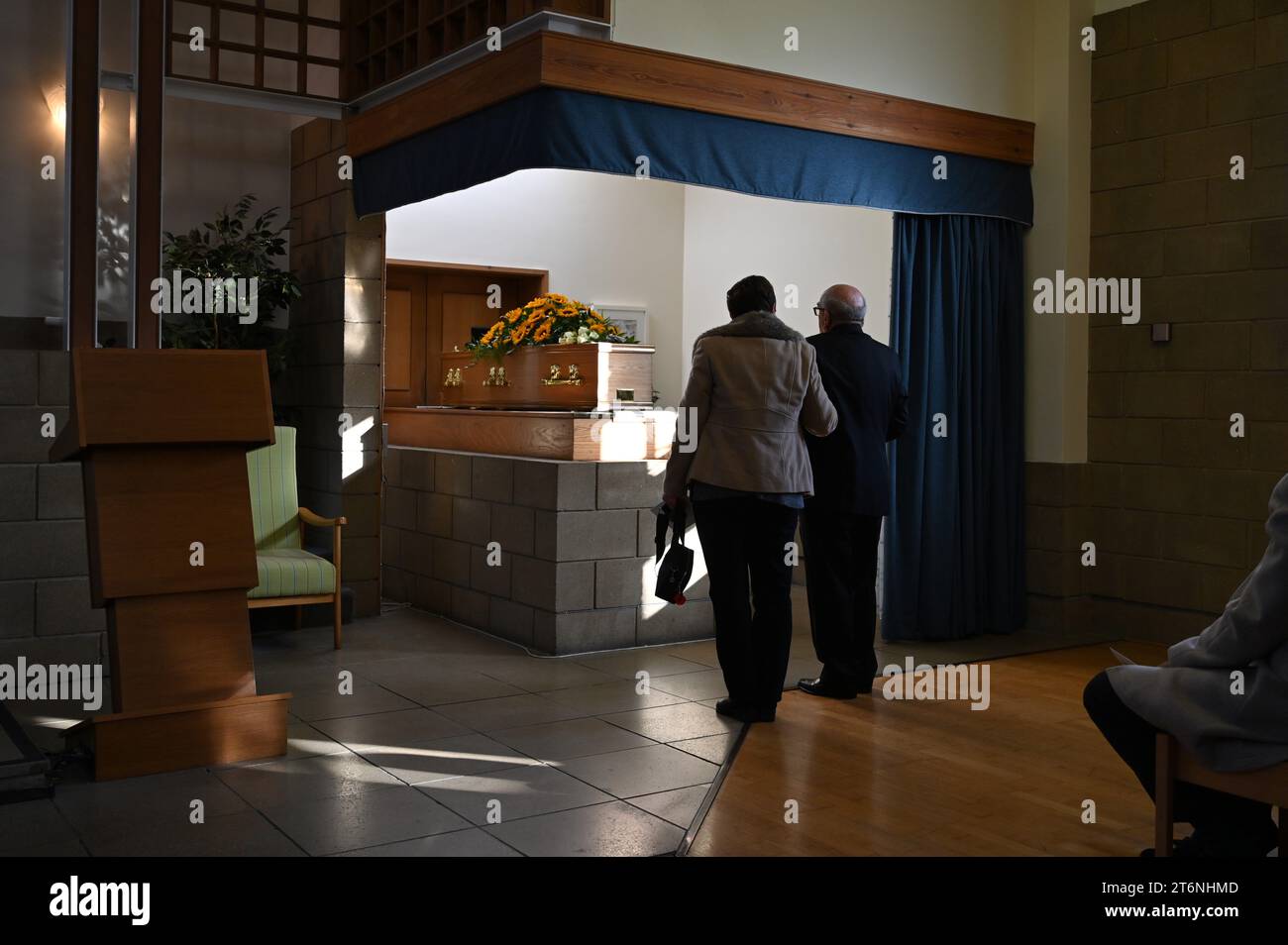 Two mourners standing in front of a coffin on a Bier at a crematorium. Stock Photo