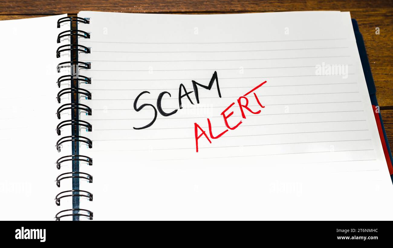 Scam alert handwriting  text on paper, on office agenda. Copy space. Stock Photo