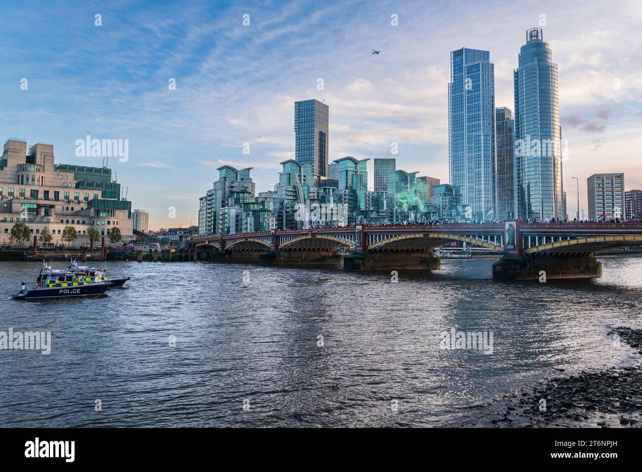 London, UK, November 11, 2023. A protest proceeding from Park Lane to the US Embassy, supporting the Palestinian cause in the Hamas-Israel conflict. Here the crowds cross Vauxhall Bridge, by the MI6 building. An airliner flies overhead. A Police Boat watches on. (Tennessee Jones - Alamy Live News) Stock Photo