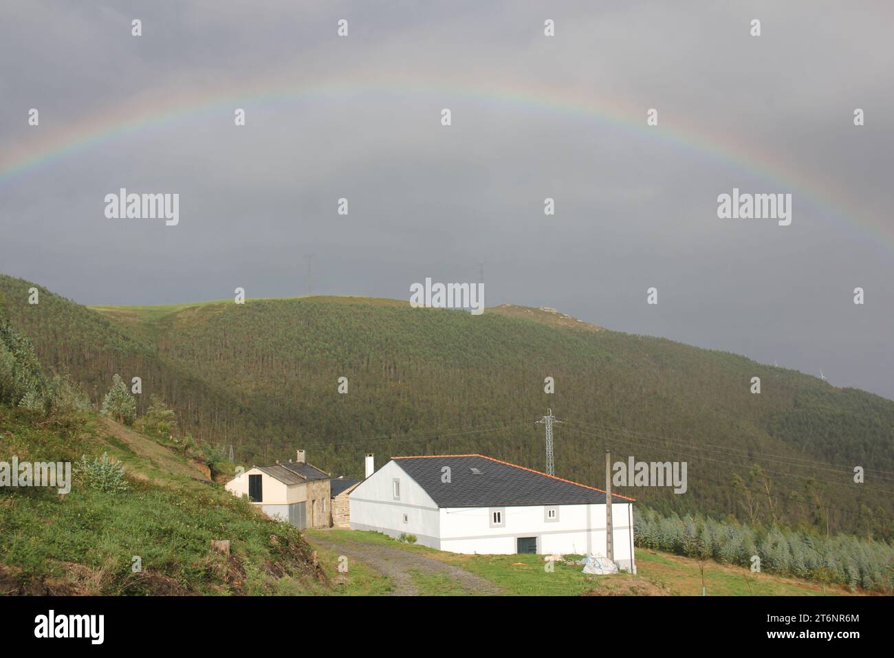 rainbow over a house in the mountains in Galicia, Spain Stock Photo