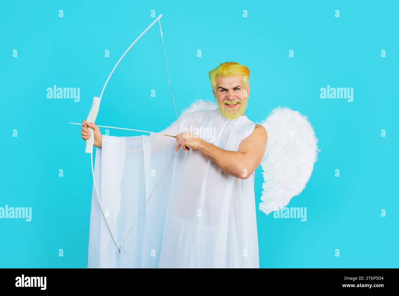 Valentine angel in white wings shoots love arrow from bow. Valentines Day celebration. Arrow of love. Smiling bearded man in angel costume shooting Stock Photo