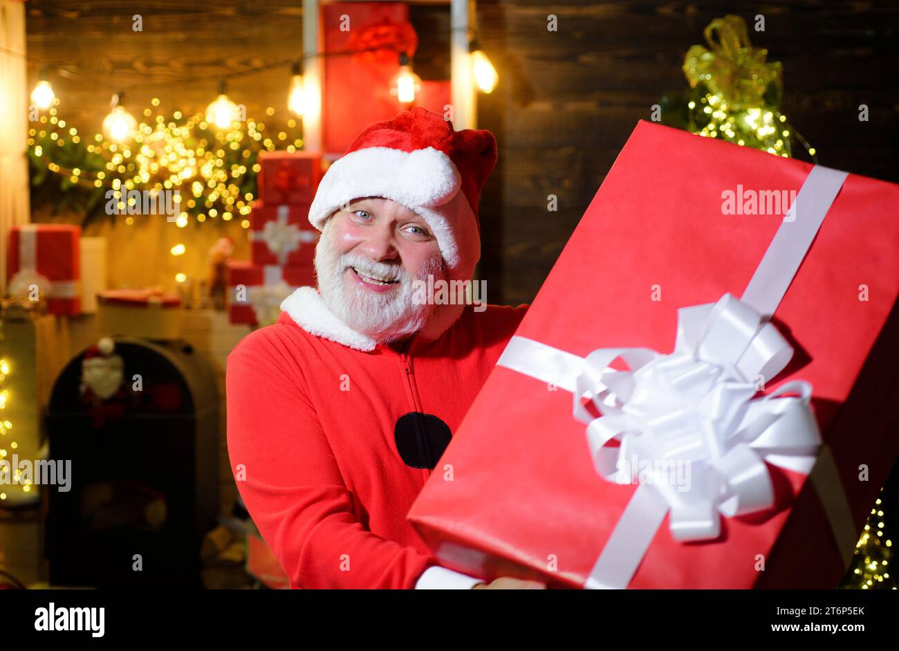 Merry Christmas and Happy New Year. Smiling Santa Claus with Christmas gift. Delivery service. Bearded man in Santa costume with big present. Winter Stock Photo