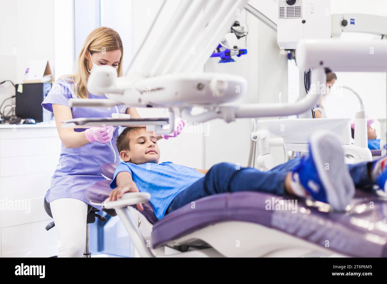 Boy leaning dental chair getting treatment by female dentist Stock Photo
