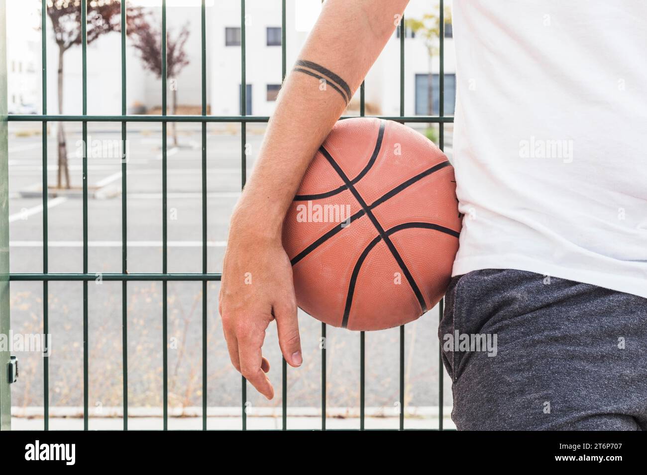 Close up man s hand with basketball front fence Stock Photo