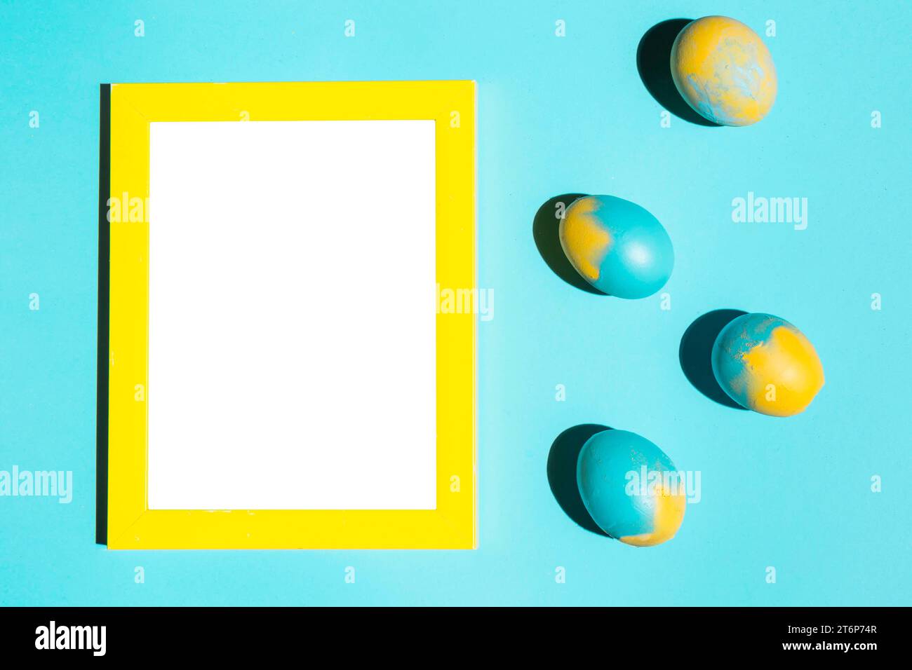 Colourful easter eggs with blank frame blue table Stock Photo