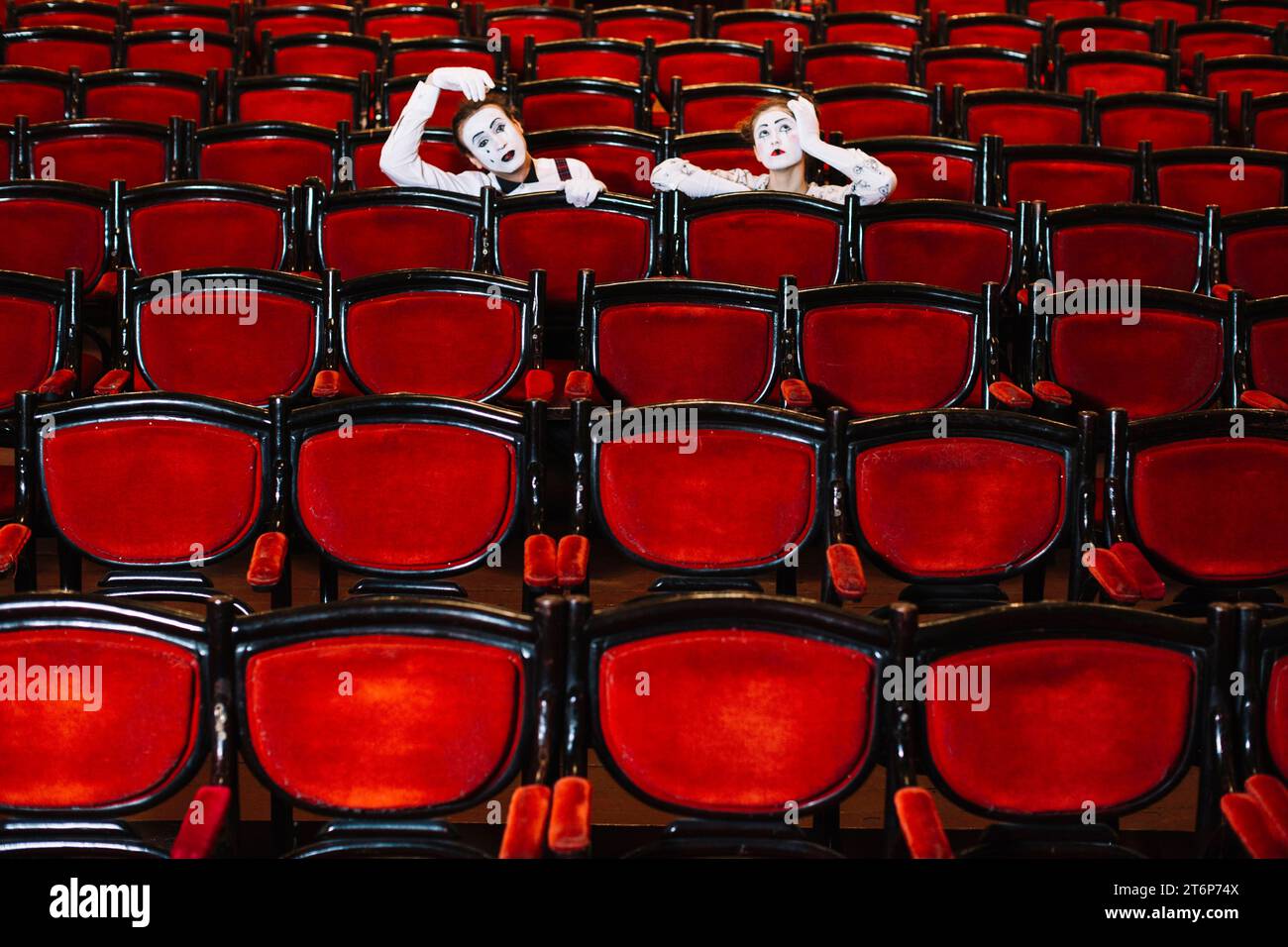 Contemplated male female mime artist sitting arm chairs Stock Photo