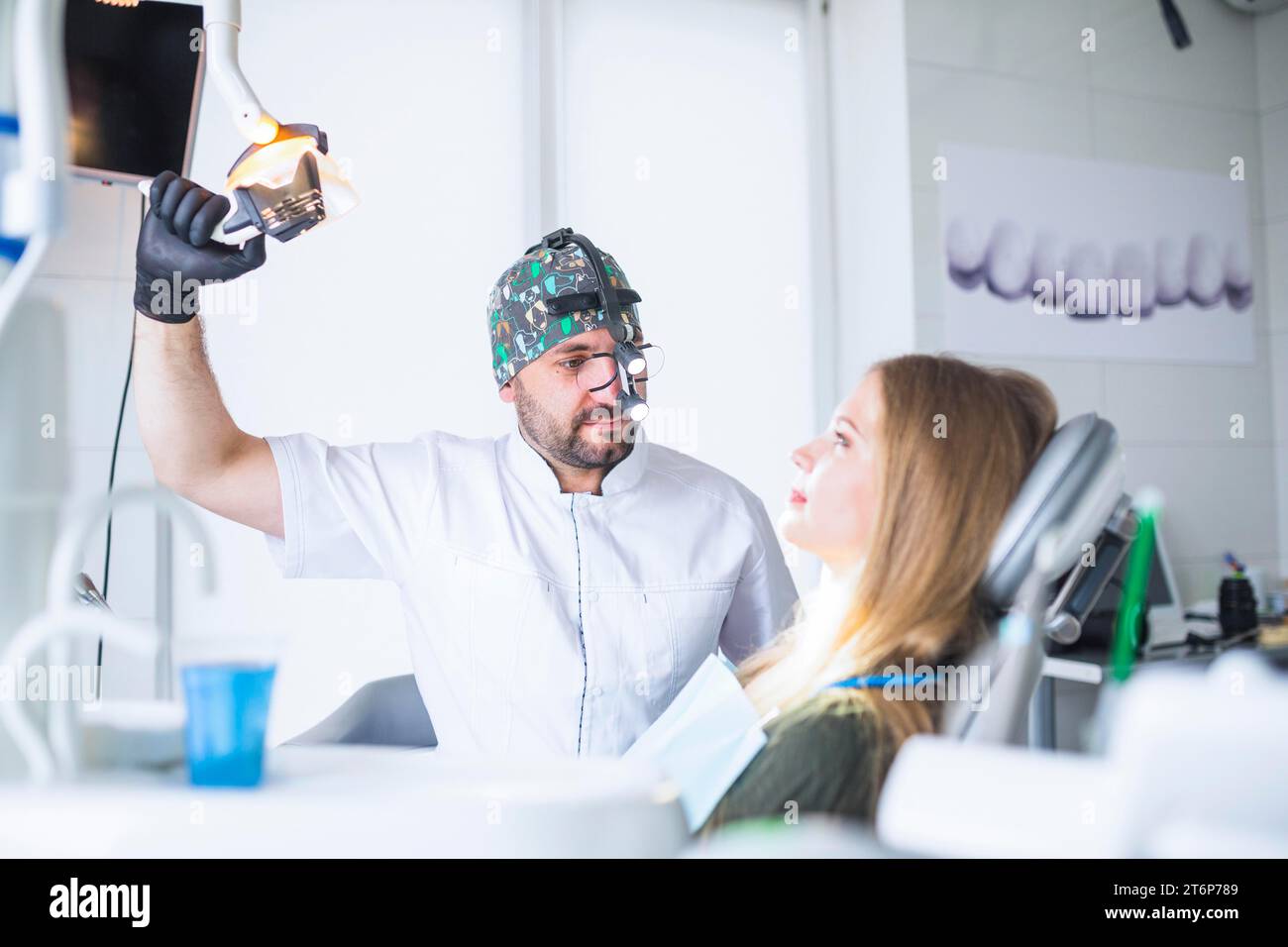 Dentist wearing dental loupe binoculars treating female patient Stock