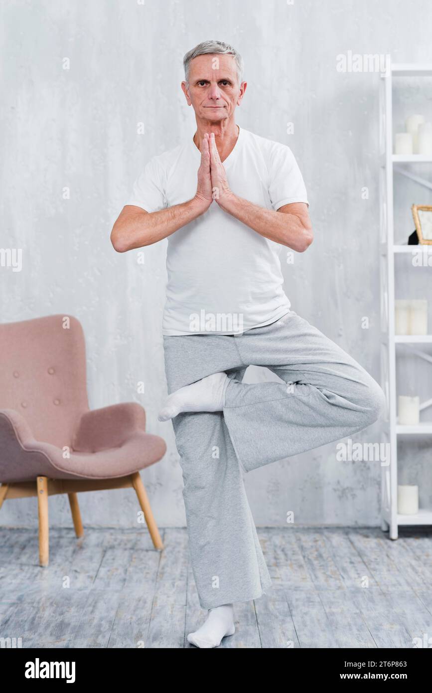 Healthy senior man practicing yoga looking camera Stock Photo