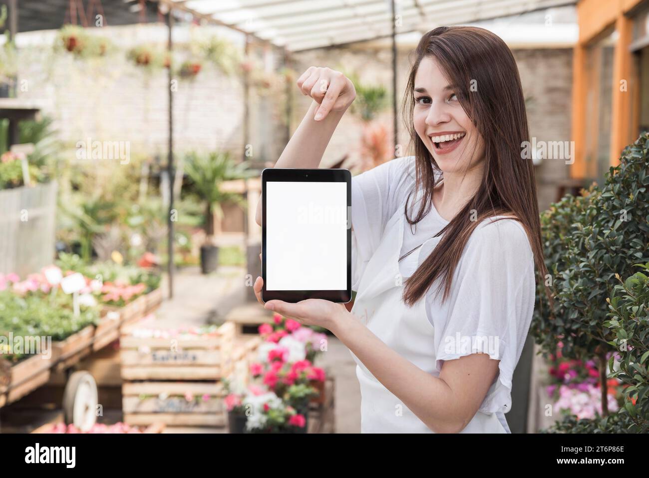 Happy woman pointing digital tablet with blank white screen Stock Photo