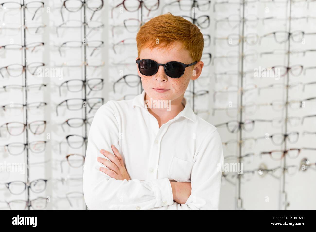 Portrait boy with black eyeglasses standing against eyeglasses background Stock Photo