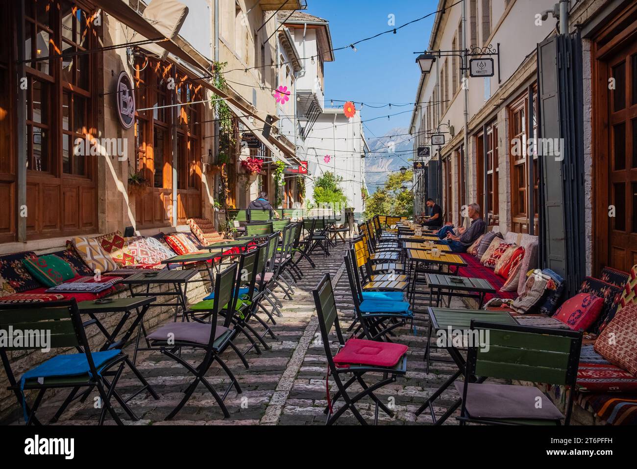 Outdoor empty coffee and restaurant terrace with colorful tables and chairs. Old fashioned cafe terrace in Berat Albania. Restaurant patio furniture. Stock Photo