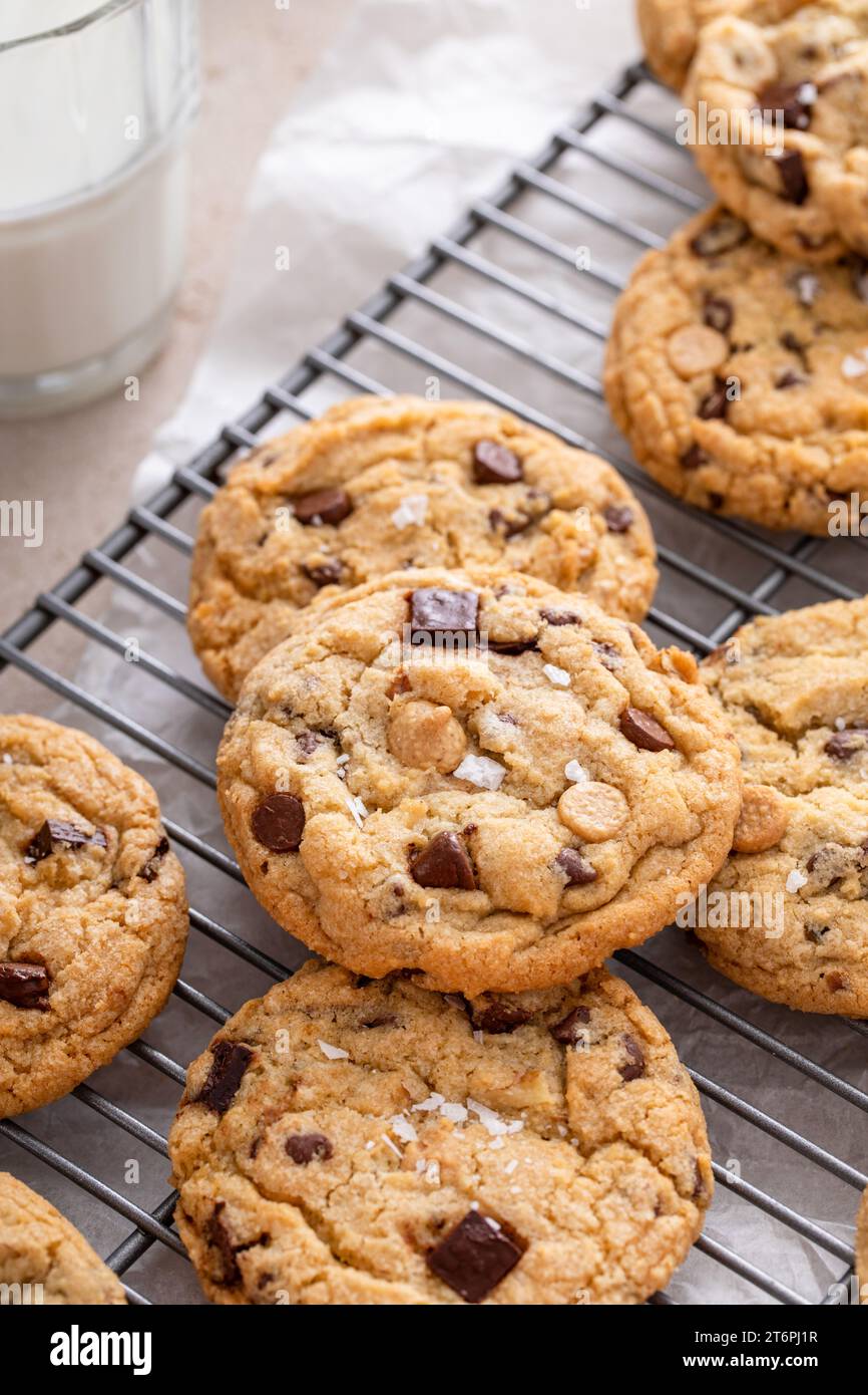 Chocolate chip cookies on a cooling rack with flaky salt served with cold milk close up shot Stock Photo