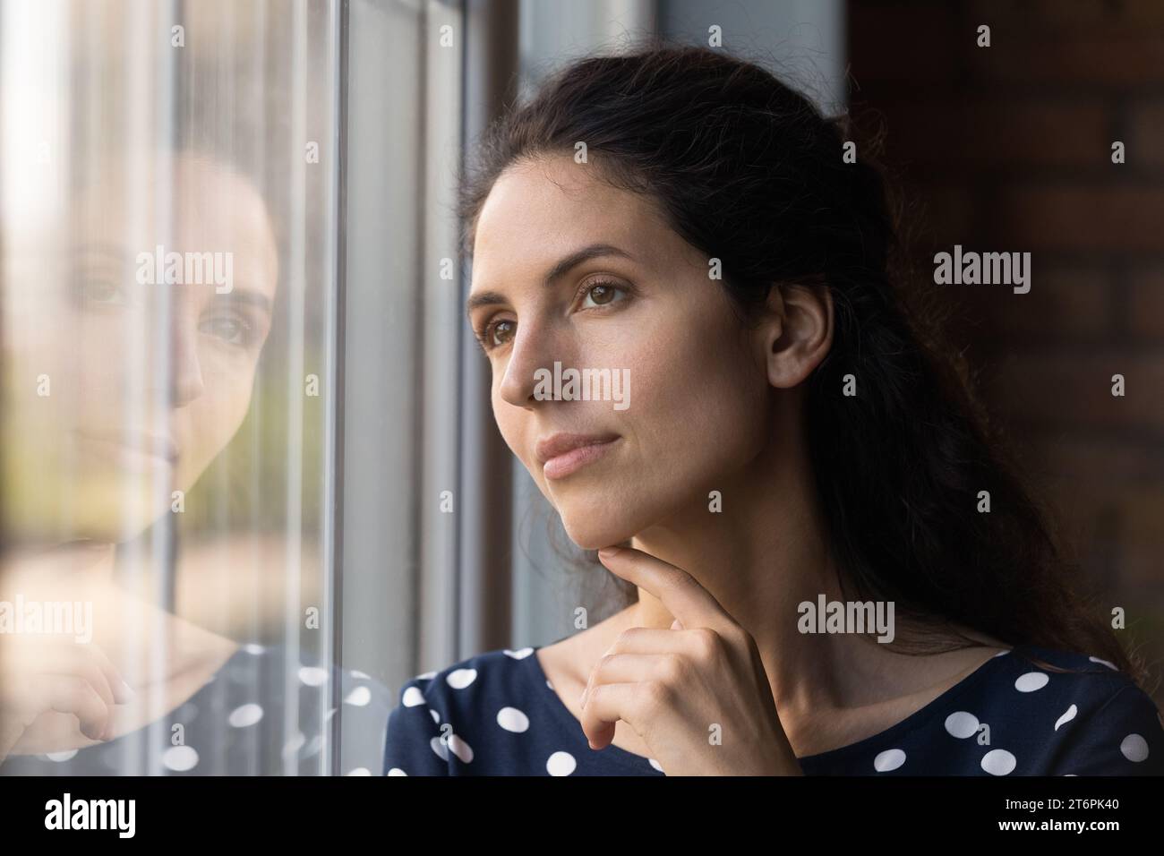 Close up dreamy woman looking out window, visualizing future Stock Photo