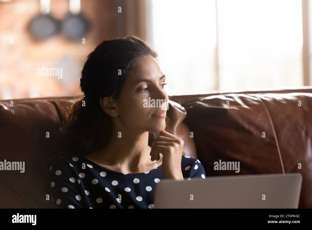 Close up thoughtful woman distracted from laptop, sitting on couch Stock Photo