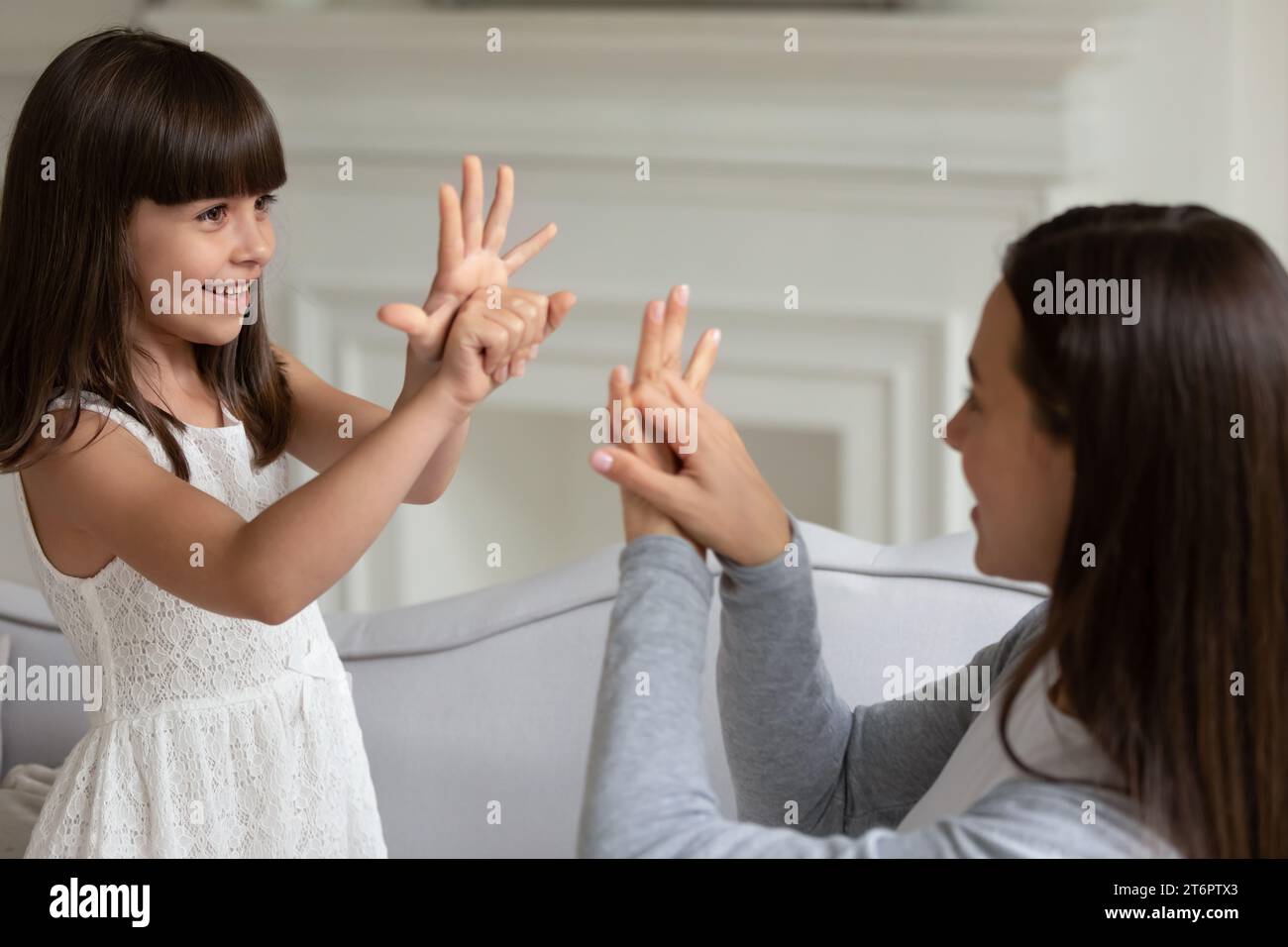 Smiling little girl and young mother speaking sign language Stock Photo