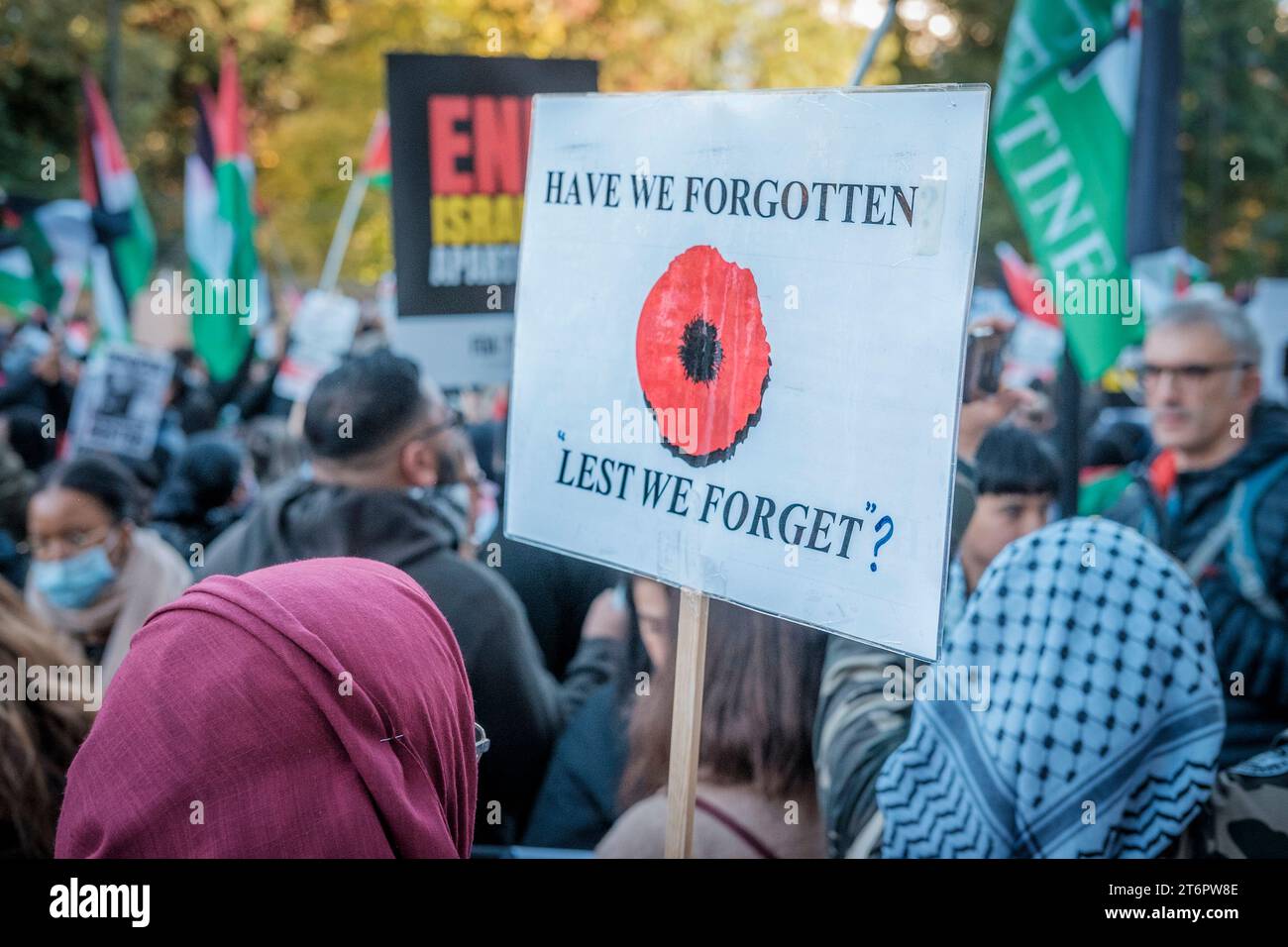 11th November 2023, London, UK. Hundreds of thousands of people march through central London in protest against Israel’s continued bombardment of Gaza. Organisers of the rally, the Palestine Solidarity Campaign, demand an immediate ceasefire. Pictured: A placard with an image of a poppy and questioning the words Lest We Forget is carried along the route. Stock Photo